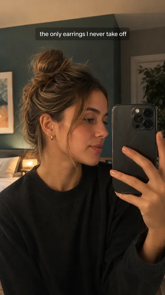 Selfie UGC de TikTok frente al espejo de una mujer enseñando sus aros dorados, con el texto los únicos pendientes que nunca me quito