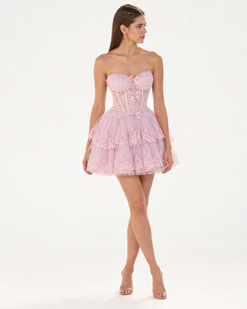 Studio product image of a model wearing a pink strapless mini dress with a tiered tulle skirt, full length on a light grey background