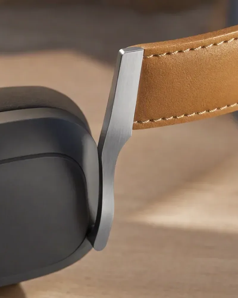 Close-up of the headphone's aluminium arm and stitched tan leather headband