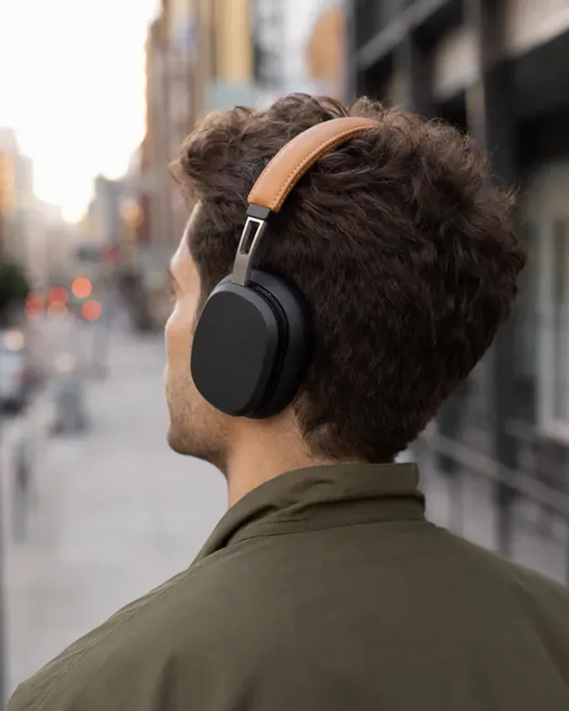 A man wearing the over-ear headphones on a city street, seen from behind