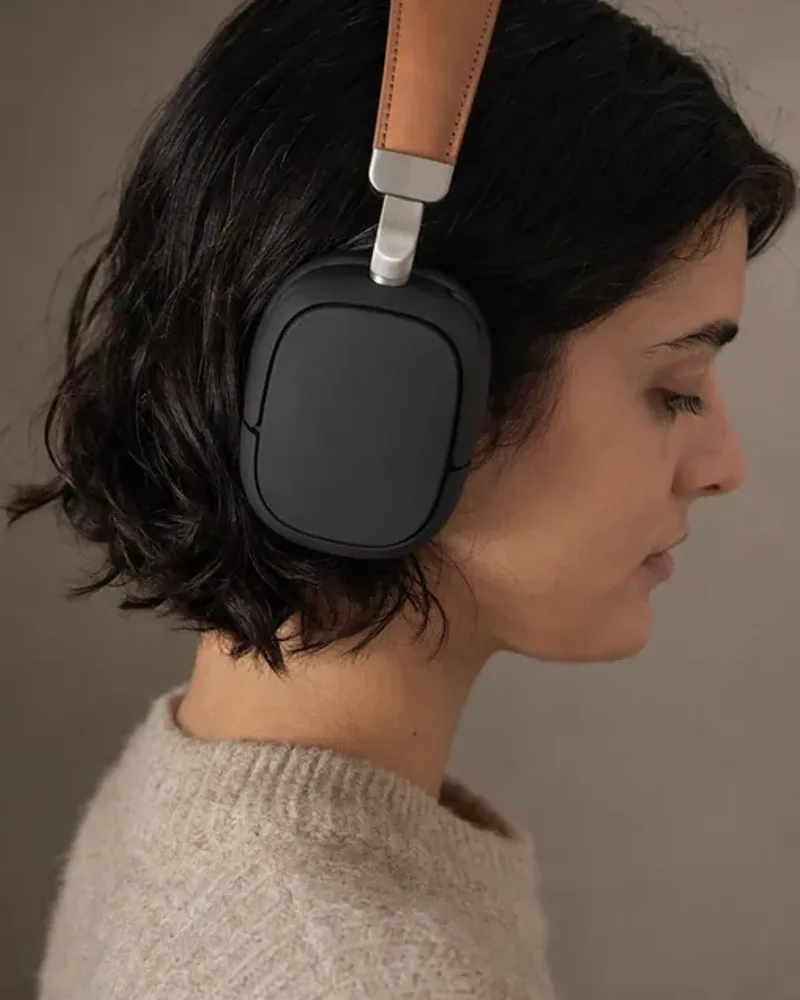 A woman wearing the black and tan over-ear headphones, seen in profile