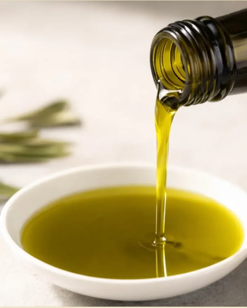 Olive oil pouring from a bottle into a small white dish