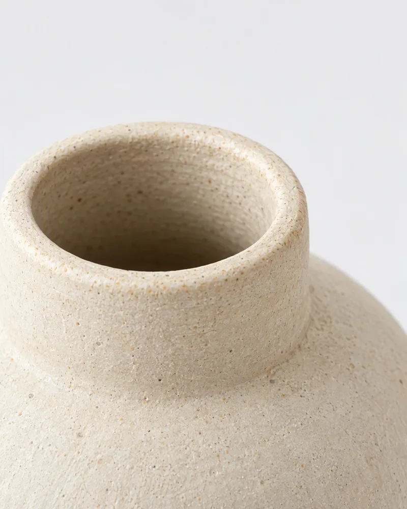 Close-up of the rounded rim and neck of the cream stoneware vase