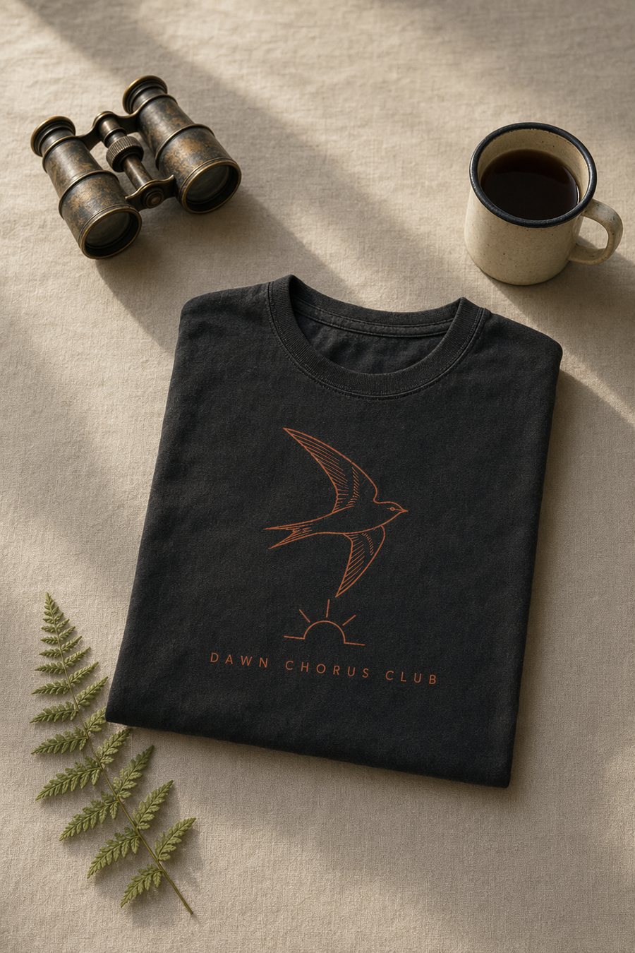 The 5AM Tee folded flat beside binoculars and an enamel mug