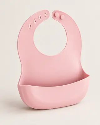 Babero de silicona rosa para bebé desde un ángulo de tres cuartos sobre fondo blanco