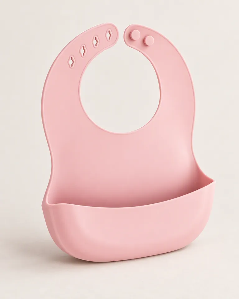 Babero de silicona rosa para bebé desde un ángulo de tres cuartos sobre fondo blanco