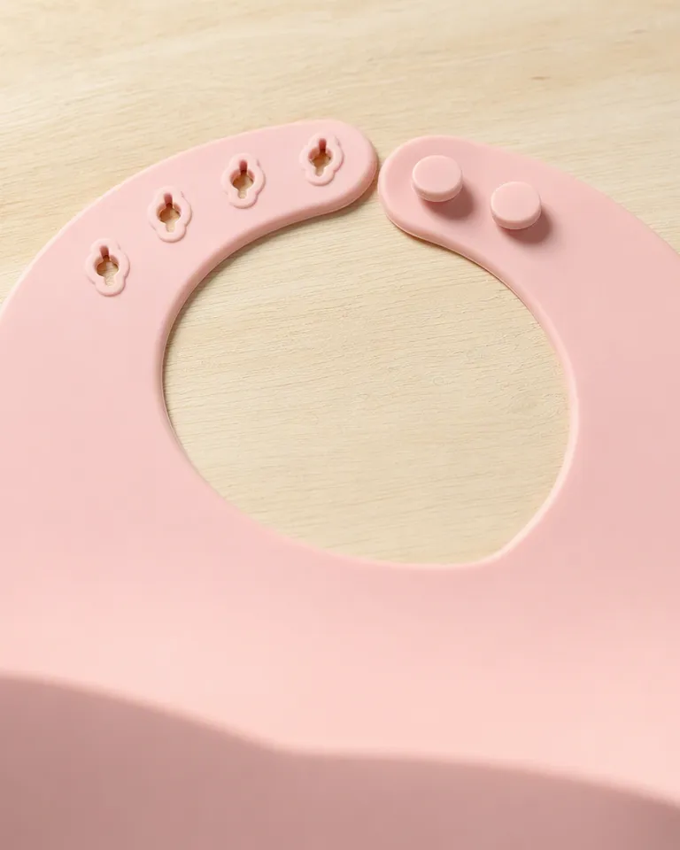Primer plano de los botones ajustables del cuello del babero de silicona rosa