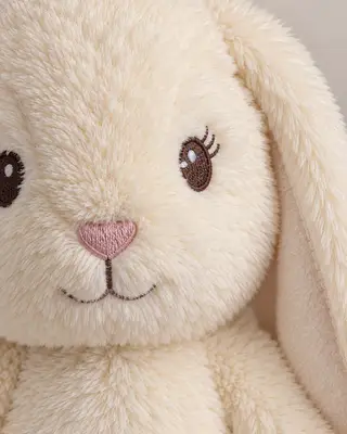 Primer plano de los ojos bordados y las orejas cosidas del conejito de peluche