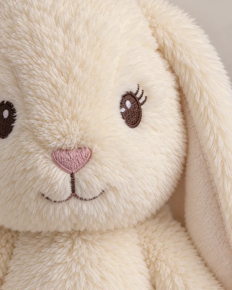 Primer plano de los ojos bordados y las orejas cosidas del conejito de peluche