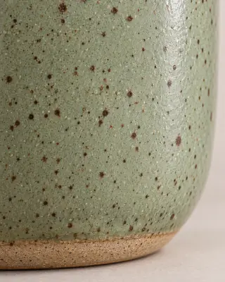 Primer plano del esmalte moteado verde salvia y la base sin esmaltar de la taza