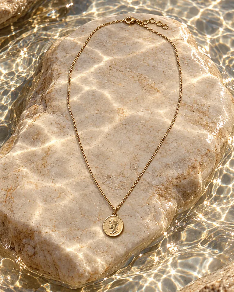 Collar de moneda dorado sobre una piedra clara en aguas poco profundas y brillantes