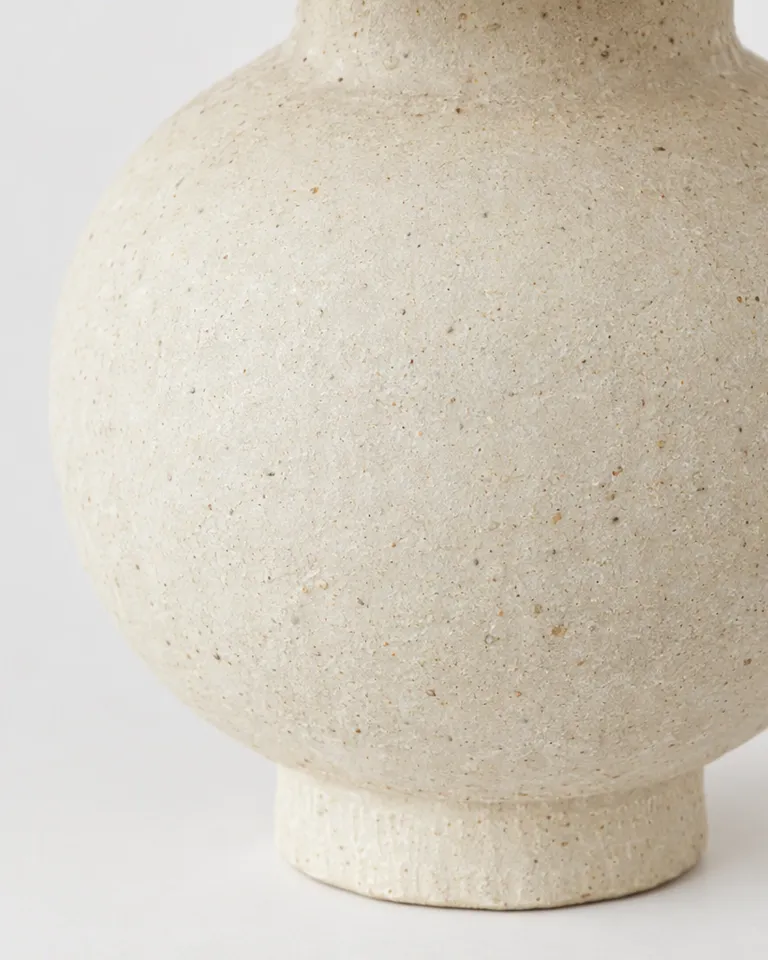Primer plano de la textura de gres moteado del jarrón crema mate