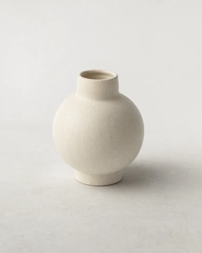 Pequeño florero de cerámica color crema solo sobre una superficie blanca para mostrar su tamaño